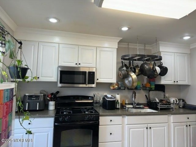 kitchen with gas stove, dark countertops, stainless steel microwave, and a sink