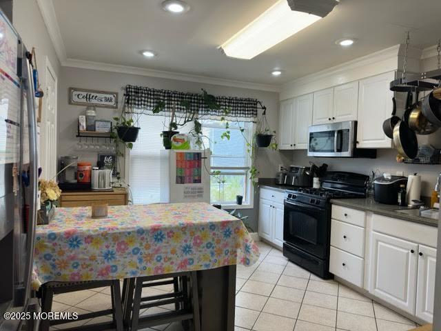 kitchen featuring crown molding, light tile patterned floors, stainless steel microwave, and gas stove