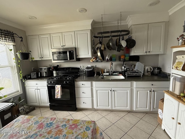 kitchen featuring black gas range, dark countertops, white cabinetry, stainless steel microwave, and a sink