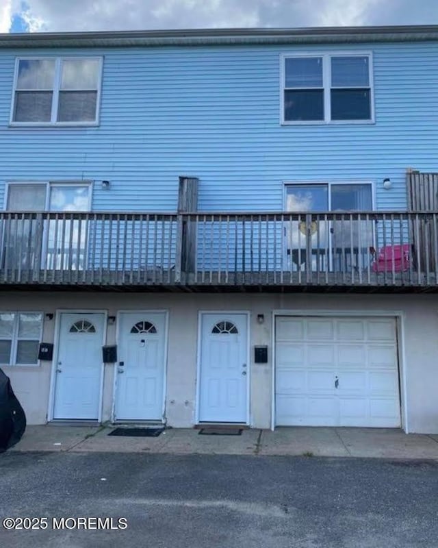 rear view of property featuring an attached garage and a balcony