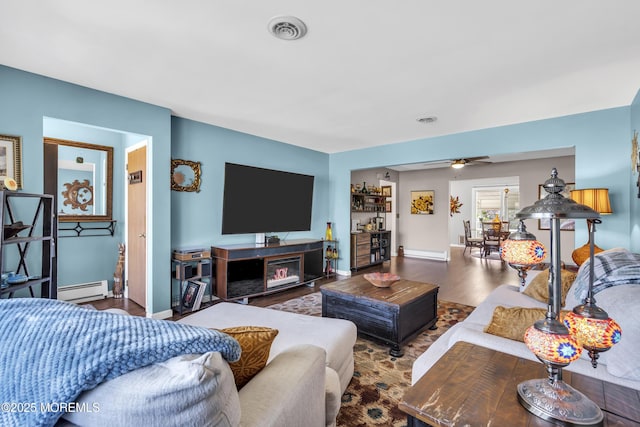 living room featuring visible vents, a ceiling fan, wood finished floors, baseboards, and a baseboard radiator