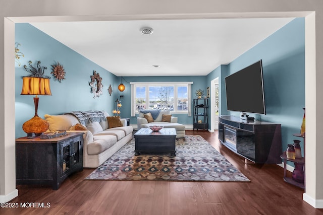 living area with baseboards, wood finished floors, and visible vents
