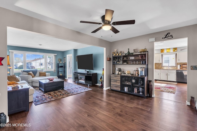 living room with dark wood-style flooring, ceiling fan, and baseboards
