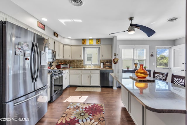 kitchen with ceiling fan, backsplash, visible vents, a sink, and stainless steel appliances