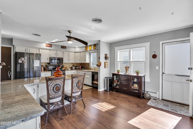 kitchen with dark wood-style flooring, ceiling fan, a sink, stainless steel appliances, and tasteful backsplash
