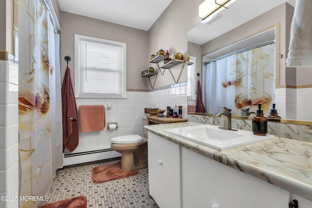 bathroom with vanity, wainscoting, toilet, tile walls, and baseboard heating