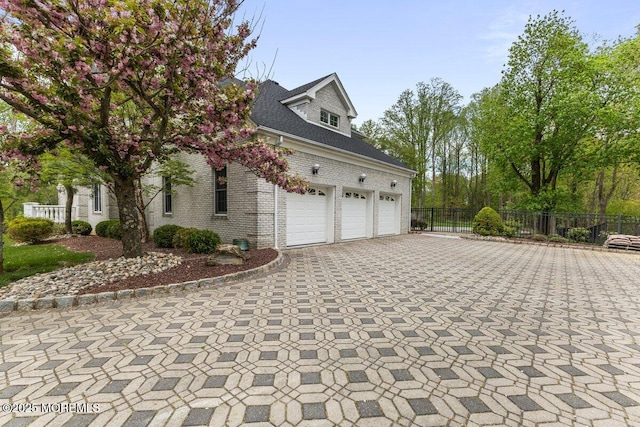 view of property exterior featuring brick siding, decorative driveway, a garage, and fence
