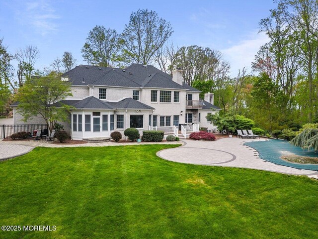 back of property with a chimney, a patio area, fence, a fenced in pool, and a balcony