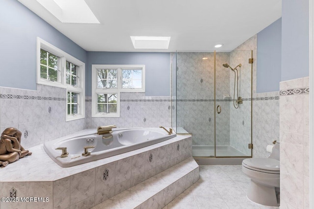 full bathroom with toilet, a skylight, tile walls, and tile patterned flooring