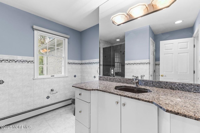 full bathroom with tile walls, tile patterned flooring, wainscoting, a stall shower, and a baseboard radiator