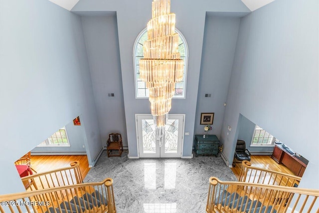 entryway with french doors, a towering ceiling, a notable chandelier, and a wealth of natural light