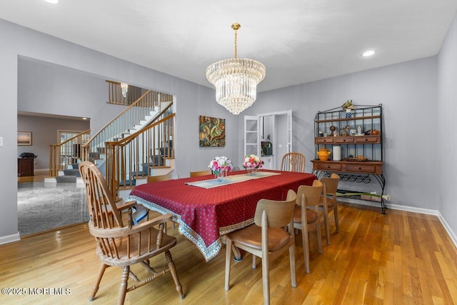 dining area featuring baseboards, a chandelier, wood finished floors, and stairway