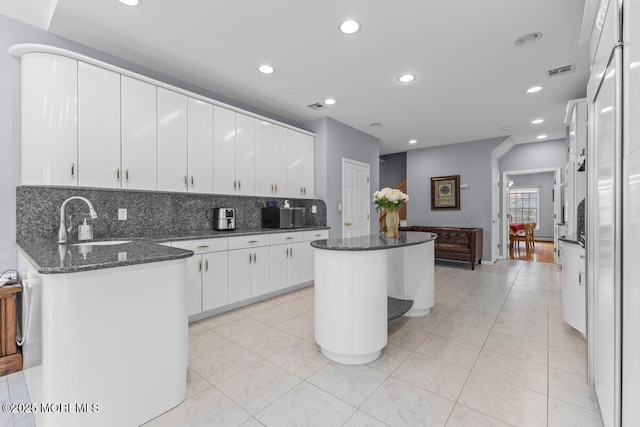 kitchen featuring visible vents, recessed lighting, white cabinetry, tasteful backsplash, and a sink