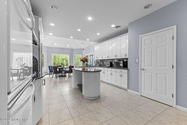 kitchen with dark countertops, a center island, recessed lighting, white cabinetry, and light tile patterned floors
