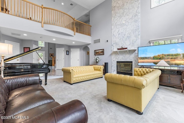 living area with visible vents, carpet, a towering ceiling, and a wealth of natural light