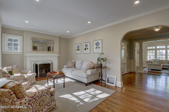 living room featuring crown molding, arched walkways, recessed lighting, and wood finished floors