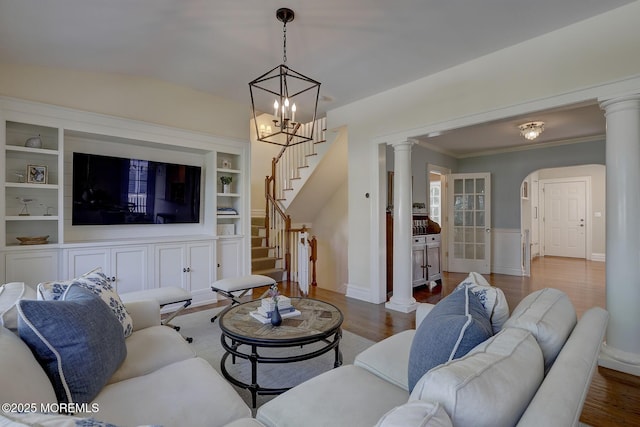 living room featuring stairway, arched walkways, ornate columns, and wood finished floors