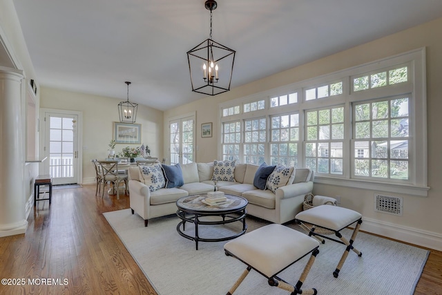 living room featuring visible vents, baseboards, wood finished floors, and a healthy amount of sunlight