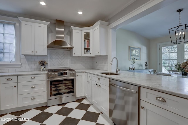kitchen with white cabinets, a sink, dark floors, wall chimney exhaust hood, and stainless steel appliances