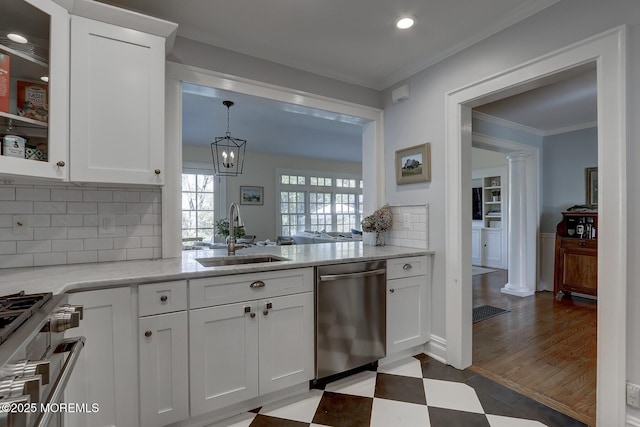 kitchen with stainless steel appliances, decorative columns, white cabinetry, and a sink