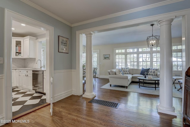 interior space with light wood-style floors, ornamental molding, ornate columns, and visible vents