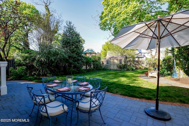 view of patio / terrace with fence, an outbuilding, and outdoor dining area