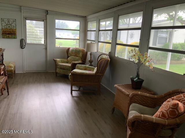 sunroom / solarium with baseboards, wood finished floors, and a healthy amount of sunlight