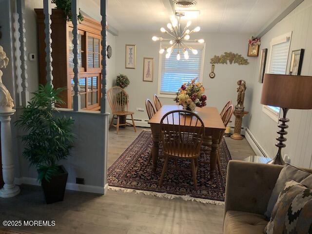 dining space with visible vents, wood finished floors, an inviting chandelier, and a baseboard radiator