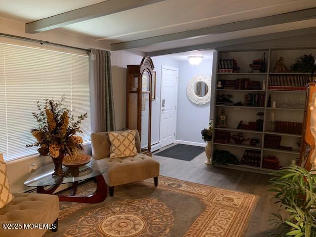 sitting room featuring beam ceiling, wood finished floors, and baseboards