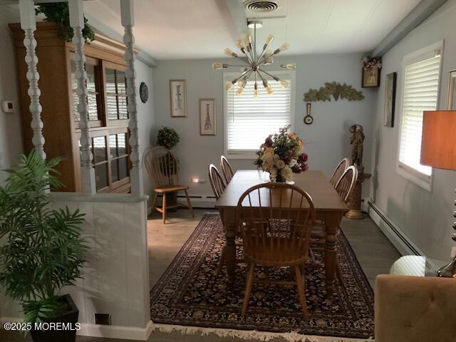 dining space featuring a baseboard radiator, wood finished floors, and a notable chandelier