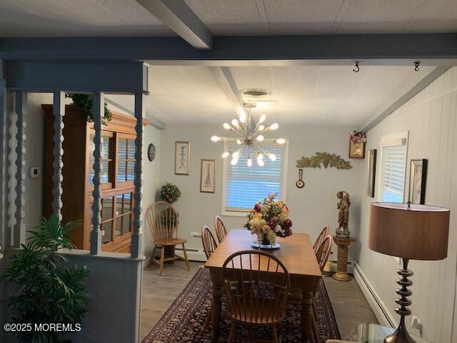 dining area featuring beamed ceiling, light wood finished floors, a notable chandelier, and a wealth of natural light