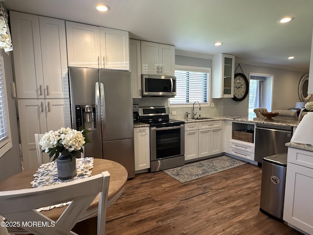 kitchen featuring dark wood-style flooring, appliances with stainless steel finishes, tasteful backsplash, a sink, and ornamental molding