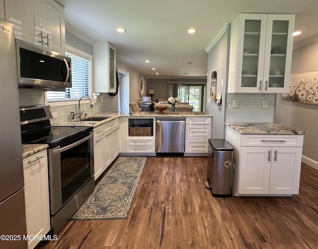 kitchen with a sink, white cabinetry, ornamental molding, and stainless steel appliances