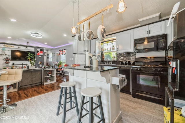 501 Ln F, Hazlet, NJ 07730 - kitchen with a healthy amount of sunlight, wood finished floors, black appliances, and a kitchen bar