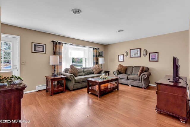 living room featuring visible vents, plenty of natural light, light wood finished floors, and a baseboard radiator