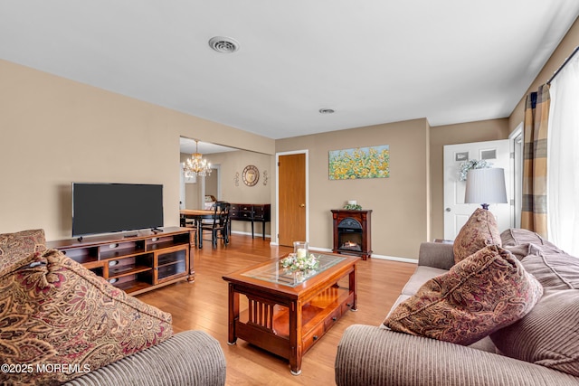 living room with an inviting chandelier, light wood-style floors, and visible vents