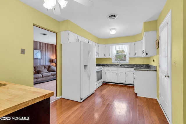 kitchen with dark countertops, white cabinetry, dark wood-style flooring, and white appliances
