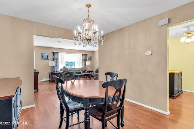 dining space featuring baseboards, a baseboard radiator, ceiling fan with notable chandelier, and light wood-style flooring