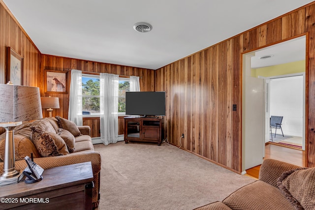 living room featuring visible vents, a baseboard radiator, wooden walls, and light carpet