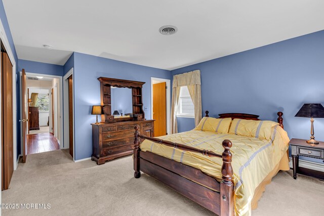 bedroom with visible vents, baseboards, a closet, and light colored carpet