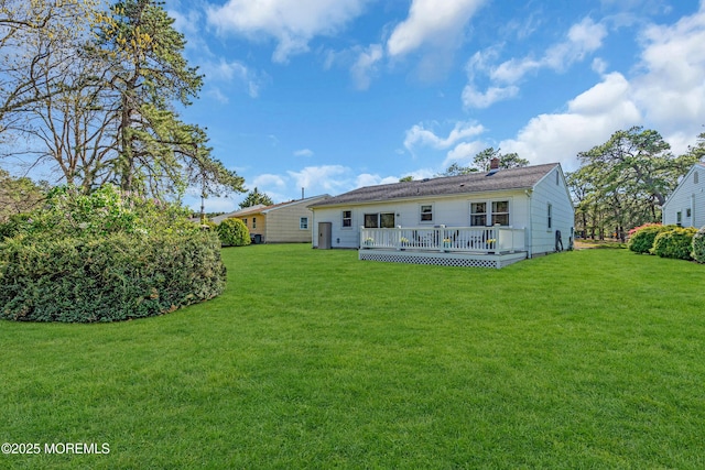 rear view of property featuring a wooden deck, a yard, and a chimney
