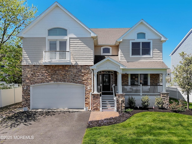 view of front of home featuring a porch, driveway, a garage, fence, and stone siding