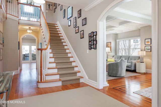 staircase featuring arched walkways, a wealth of natural light, and hardwood / wood-style floors