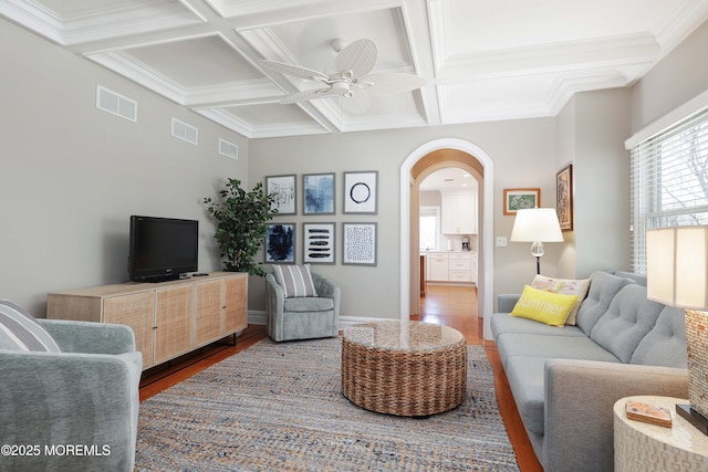 living area with a ceiling fan, visible vents, arched walkways, wood finished floors, and coffered ceiling