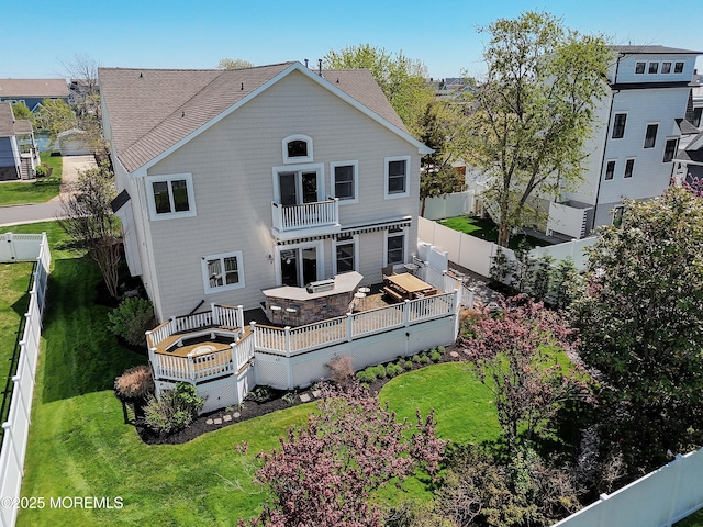 rear view of property with a fenced backyard, a wooden deck, a lawn, and a balcony