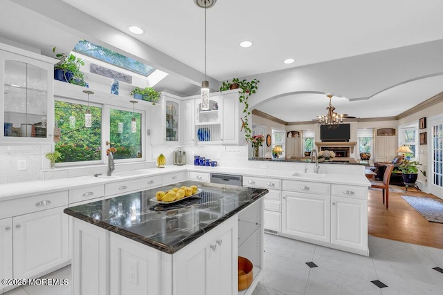 kitchen with open floor plan, a chandelier, glass insert cabinets, and a sink
