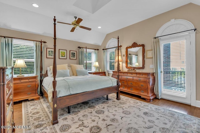 bedroom with access to exterior, multiple windows, wood finished floors, and lofted ceiling