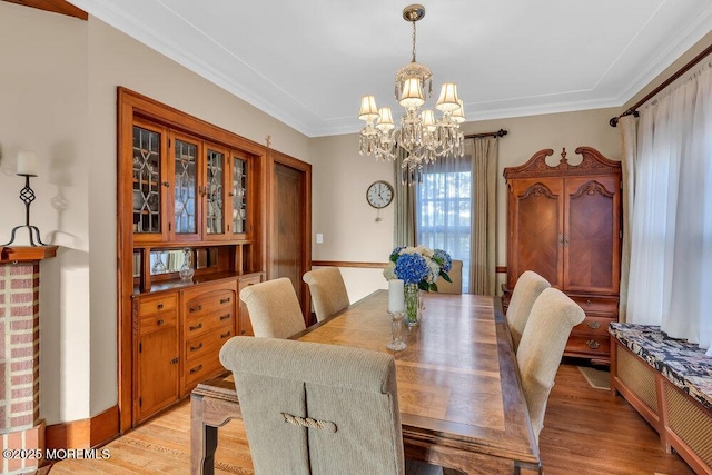 dining area featuring an inviting chandelier, ornamental molding, and light wood finished floors