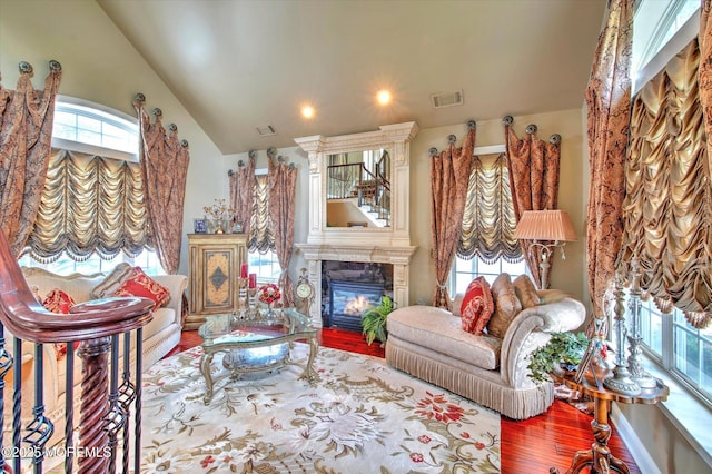 living area featuring visible vents, a large fireplace, wood finished floors, lofted ceiling, and recessed lighting