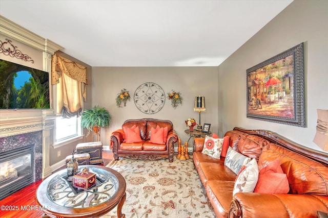 living area featuring baseboards, a glass covered fireplace, and wood finished floors
